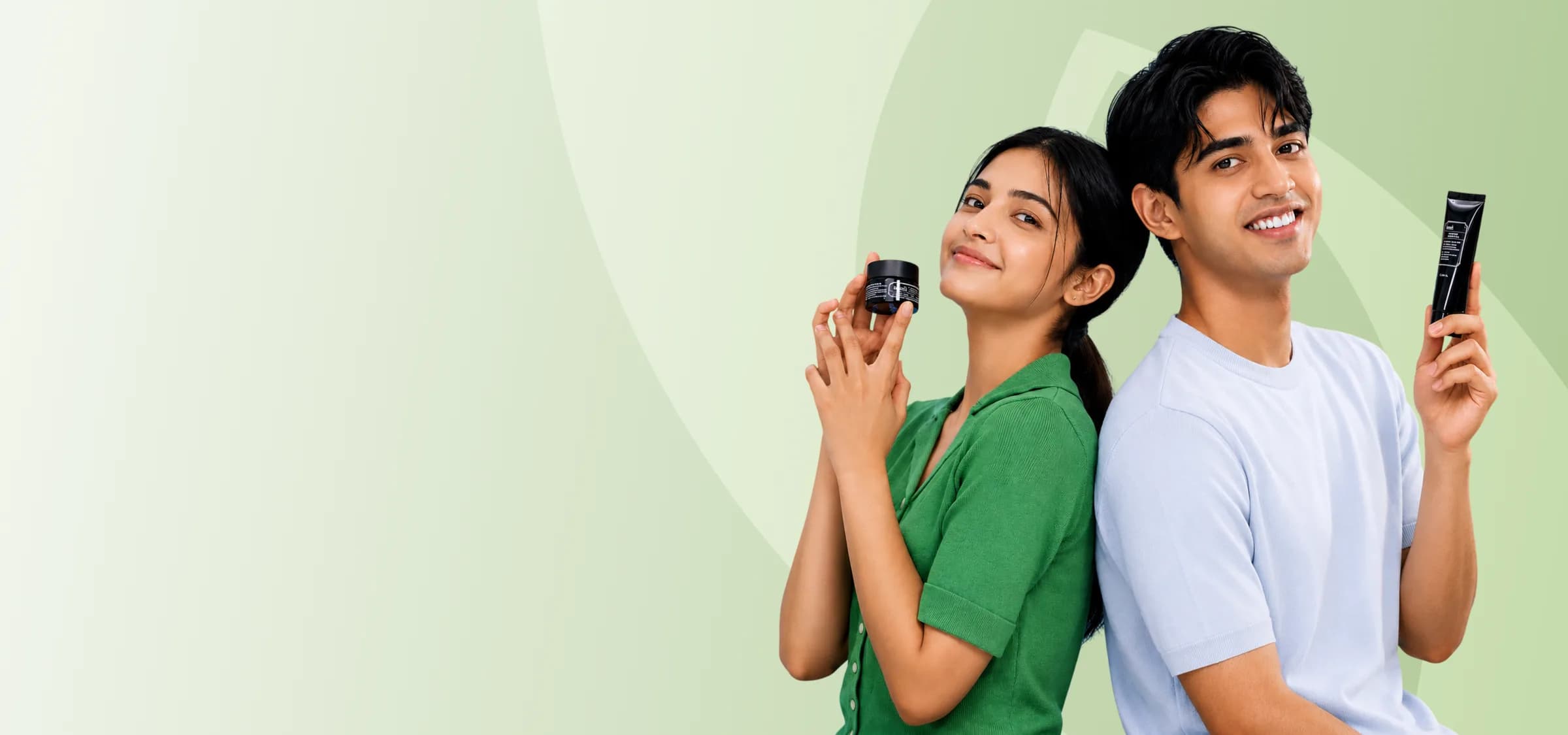 Two people holding Verda skincare products against a green backdrop